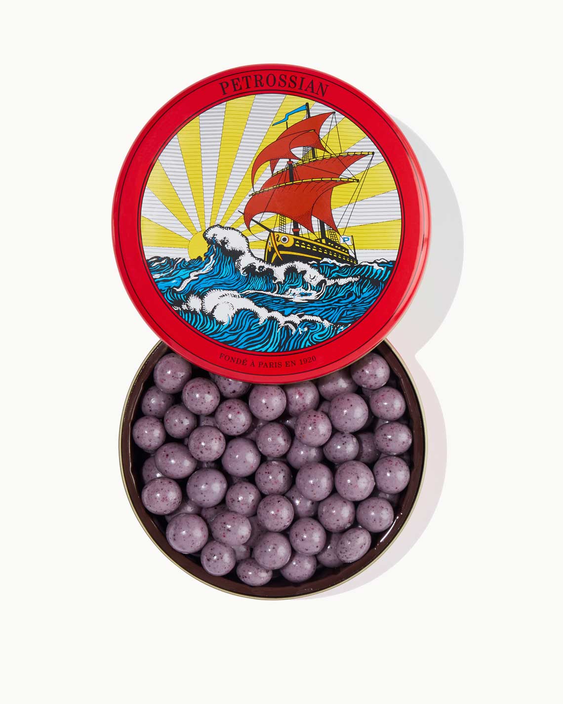 a red Petrossian tin filled with purple chocolate covered blueberries