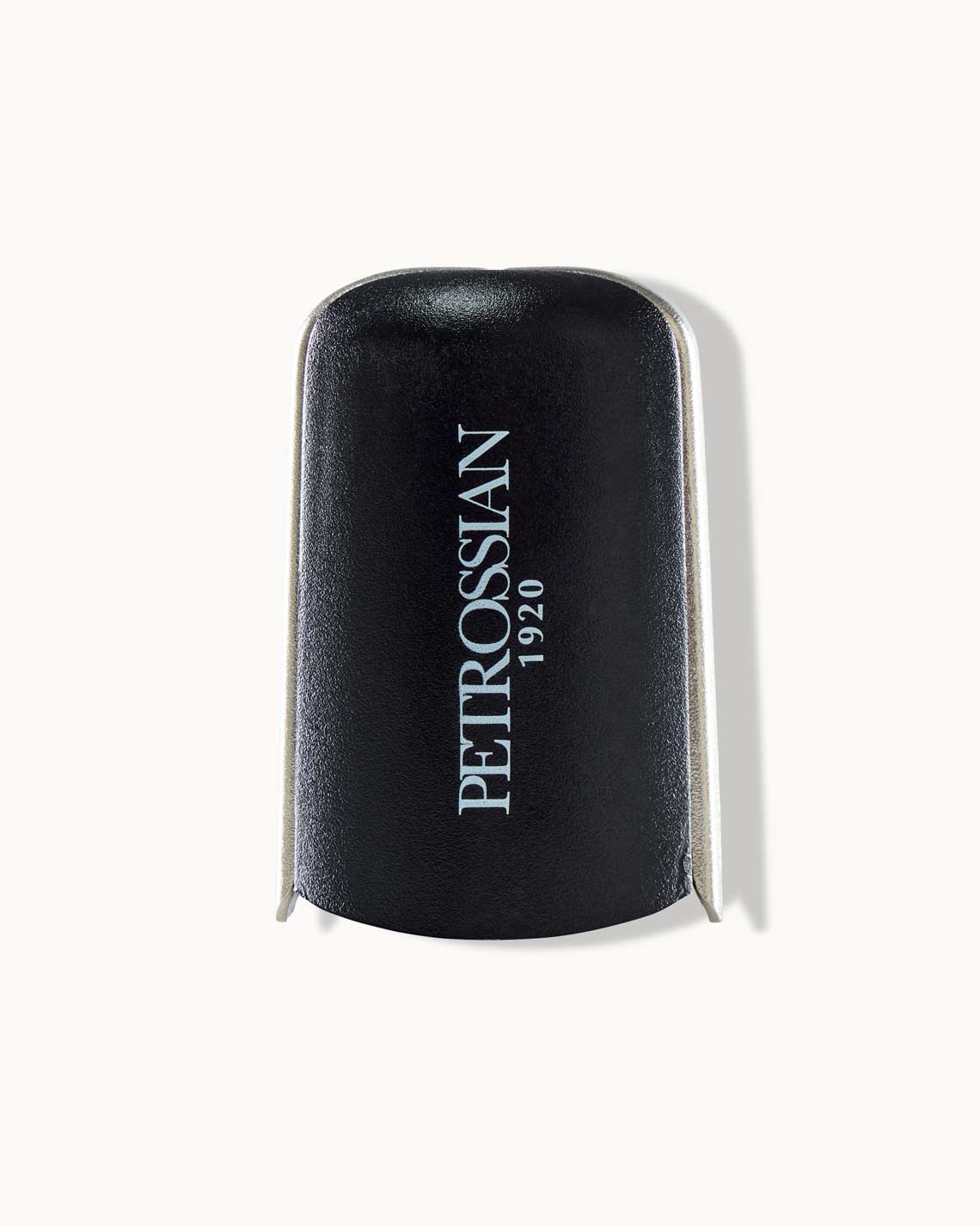 a black and silver champagne saver rests on a white background. it's clamps are folded in and "Petrossian 1920" is written along the side.