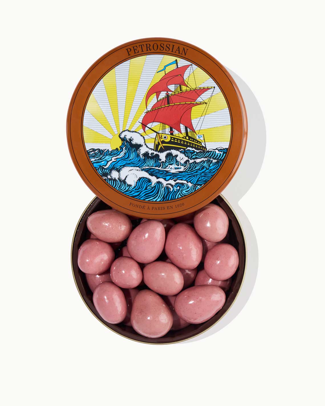 a green metal tin with the Petrossian logo, filled with large pink chocolate beads on a white background