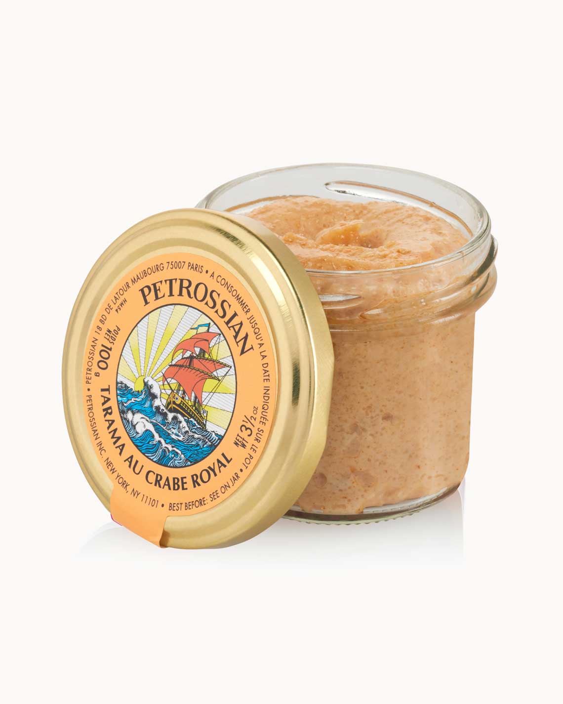 an open glass jar with a copper lid and a orange label is filled with creamy crab tarama, sitting on a white background.