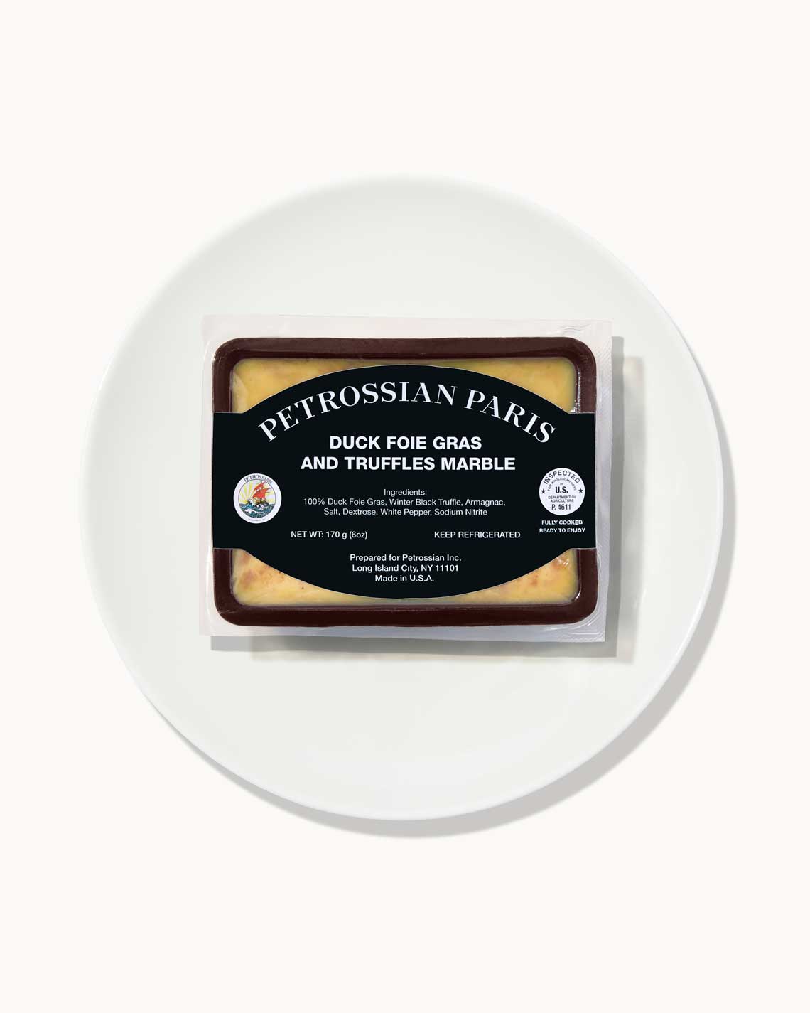 a brown terrine of yellow-beige truffled foie gras sits on a white plate on a white background.