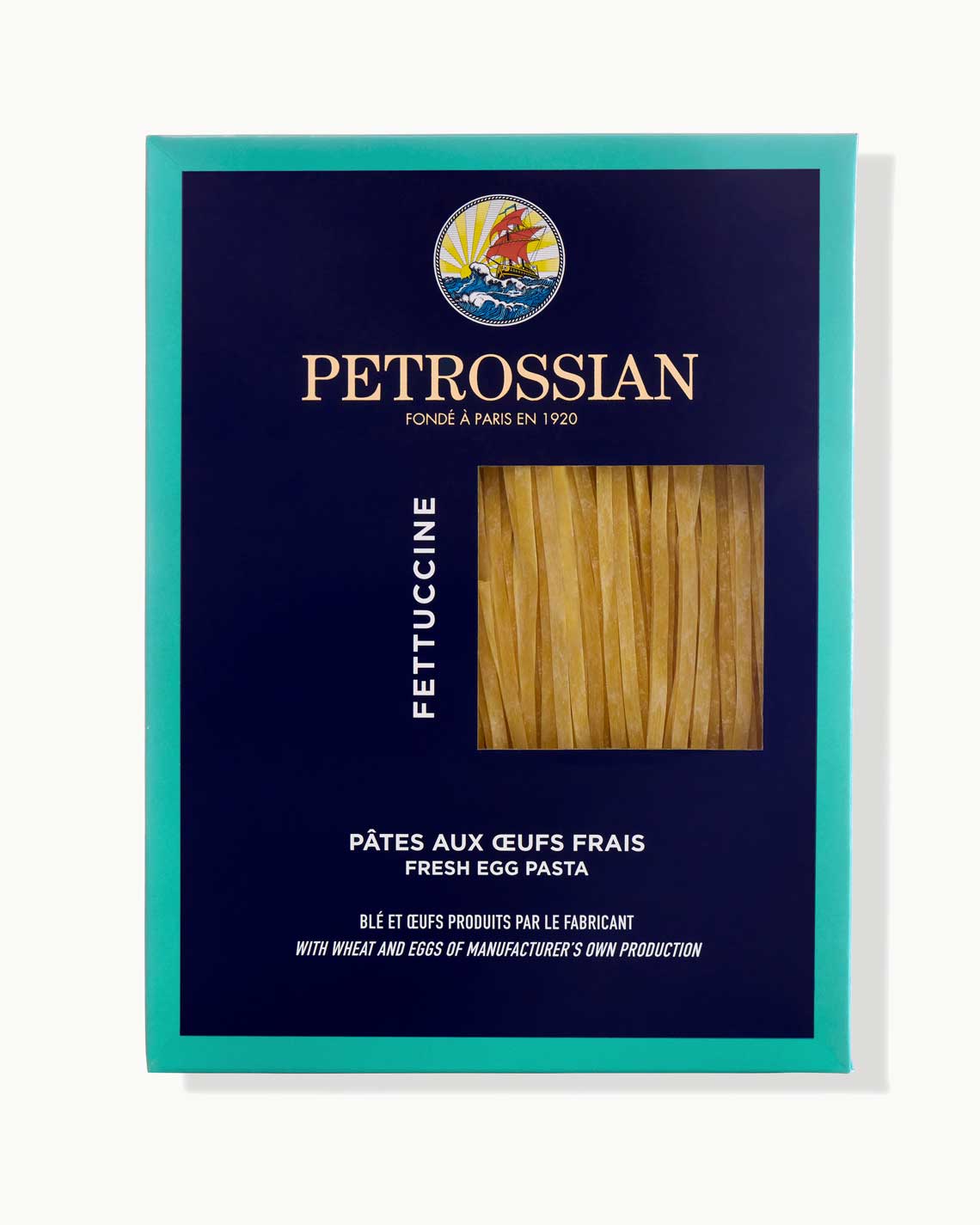 a navy blue Petrossian box with a teal trim.  Through a cut-out in the box, a light brown thick fettuccine can be seen