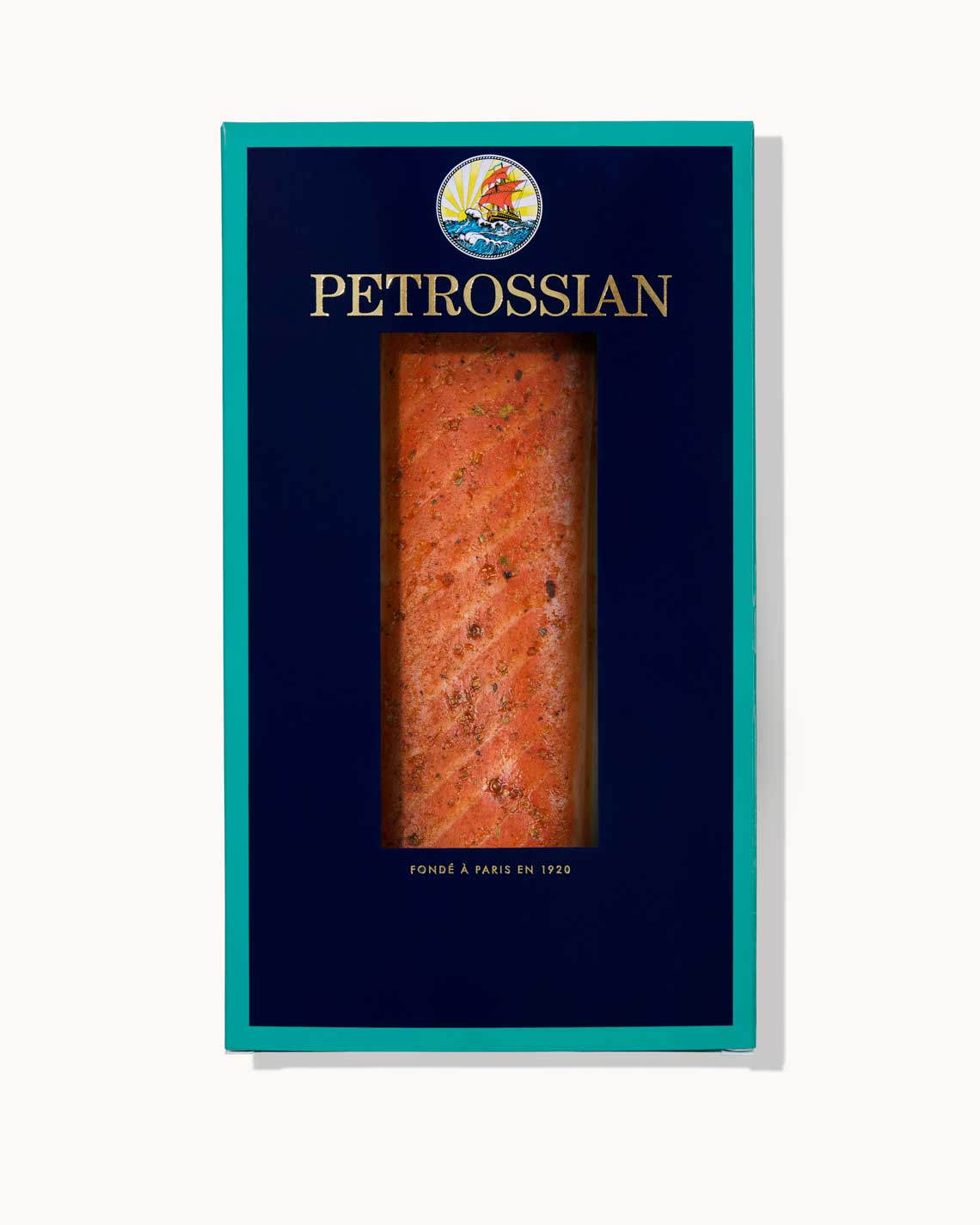 A navy blue Petrossian box with teal trim sits on a white background. A juicy filet of rich spiced smoked salmon can be seen through a cut-out in the center of the box.