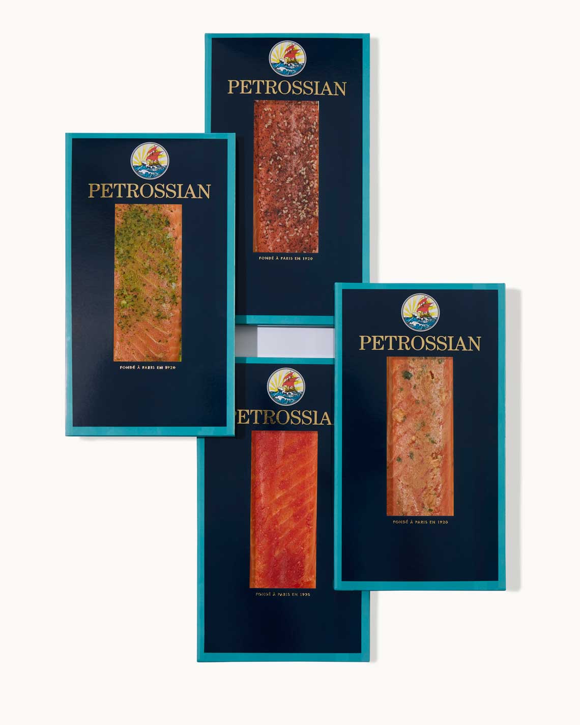 Four navy blue Petrossian boxes with teal trim sit on a white background. A juicy filet of rich Smoked Salmon can be seen through a cut-outs in the center of each box.