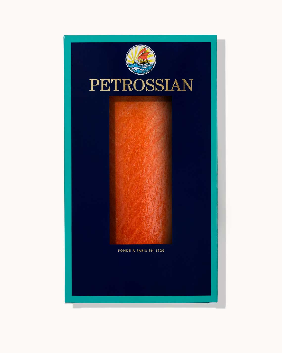 A navy blue Petrossian box with teal trim on a white background. A juicy vibrant orange filet of rich smoked salmon can be seen through a cut-out in the center of the box.