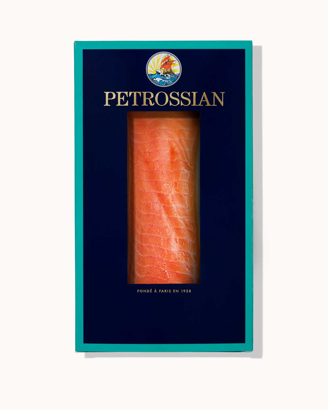 A navy blue Petrossian box with teal trim on a white background. A juicy orange filet of rich smoked trout can be seen through a cut-out in the center of the box.