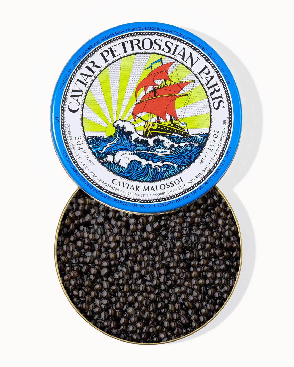 A top down image of an opened blue tin of Petrossian caviar, sitting on a white background. The tin is filled with plump, glistening dark black  beads of Beluga-Hybrid caviar.