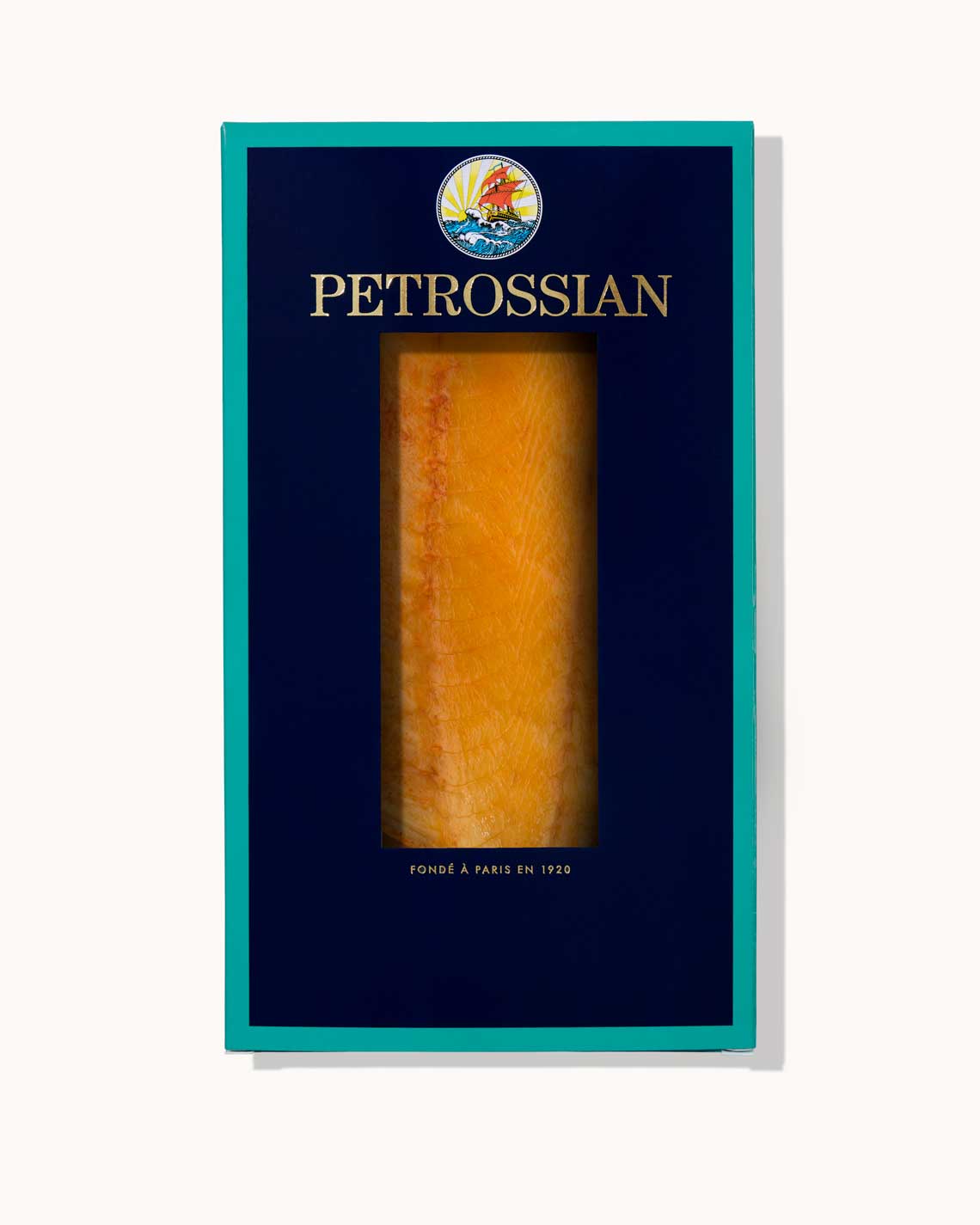 A navy blue Petrossian box with teal trim on a white background. A juicy filet of Yuzu Smoked Salmon can be seen through a cut-out int he center of the box.