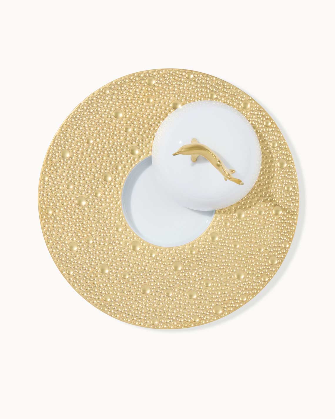 a top-down image of a golden bubble-pattern plate with a place for a caviar tin and an ecume lid topped with a golden sturgeon