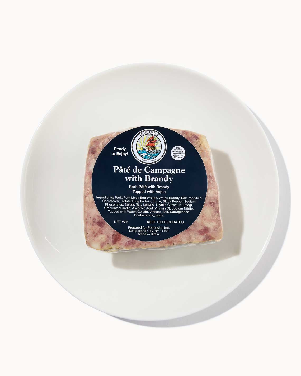a healthy loaf of brandy pate ona. white plate with a navy Petrossian label