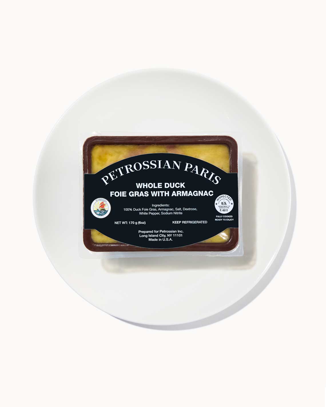 a brown terrine of yellow-beige truffled foie gras sits on a white plate on a white background.