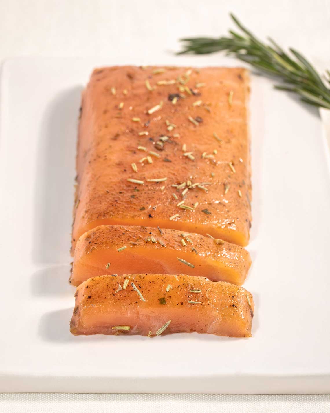 a thick cut filet of smoked trout is plated with an herb garnish. it is topped with additional herbs.