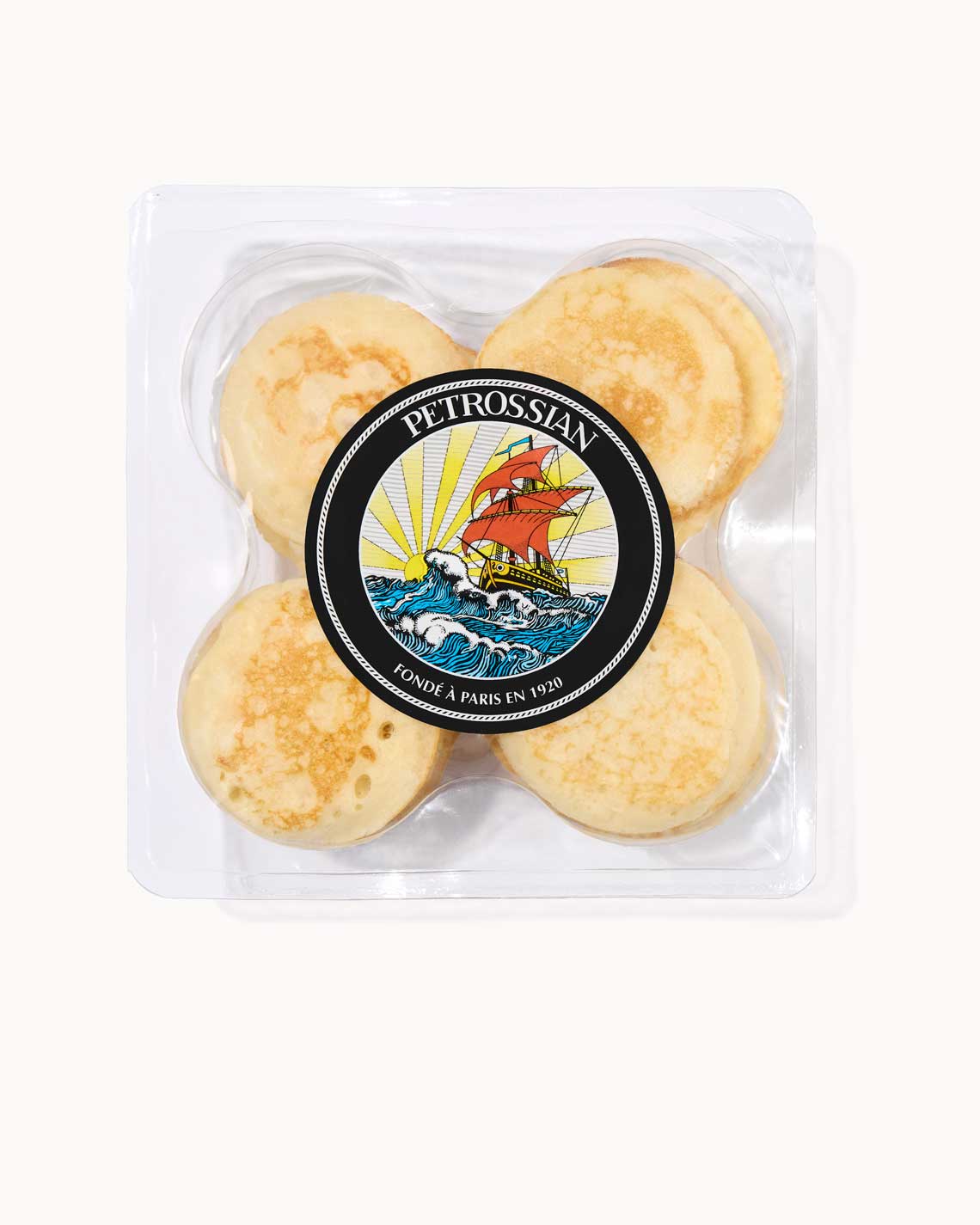 a clear plastic package, filled with sixteen lightly brown blinis, labeled with a Petrossian logo