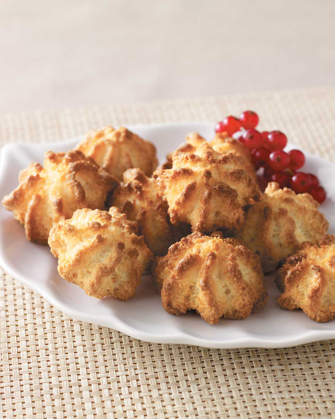a white plate with golden brown macaroons and red berries