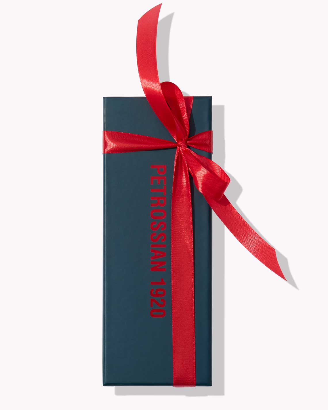 a long navy blue Petrossian box wrapped in a wide red ribbon on a white background
