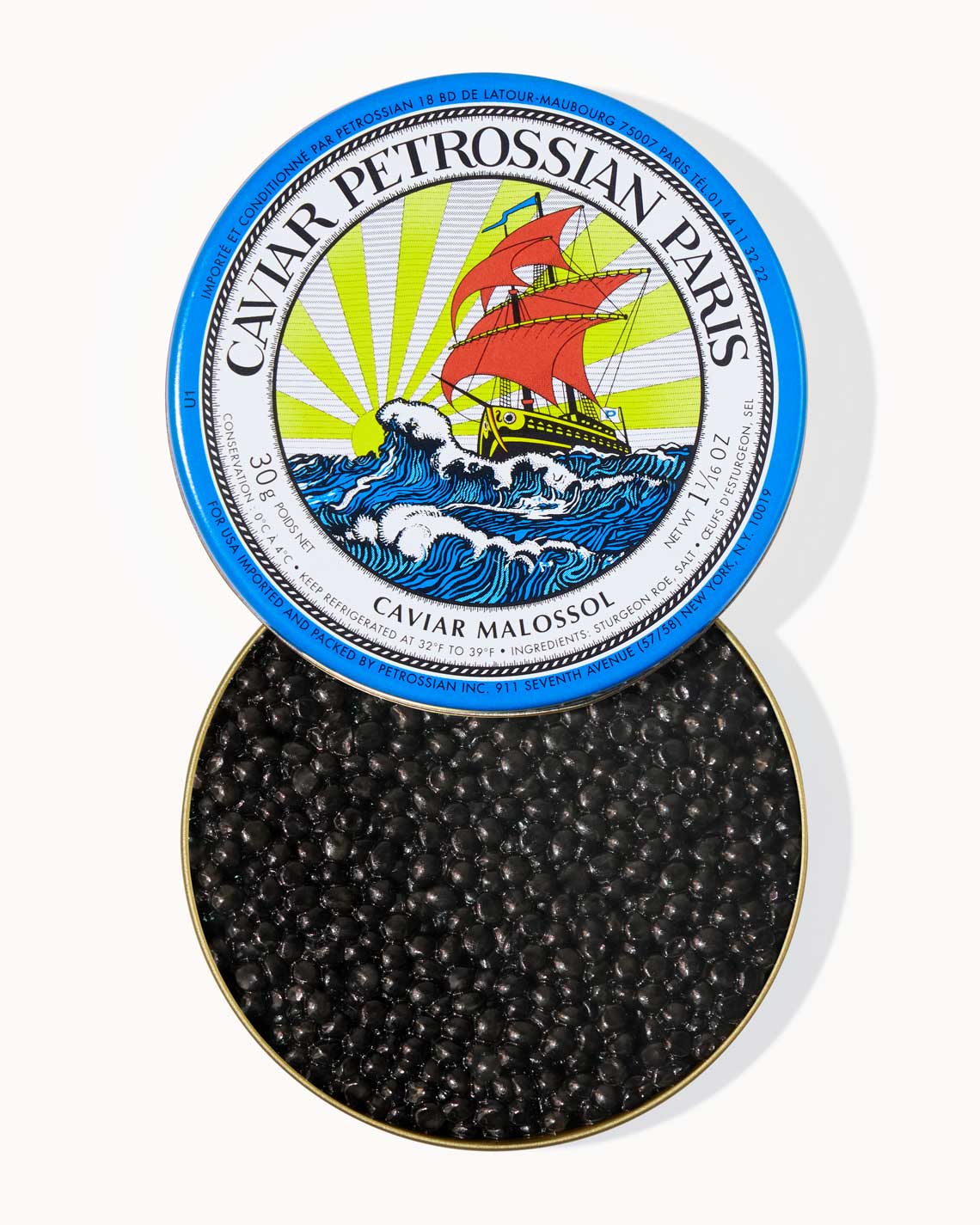 a top-down shot of a blue Petrossian caviar tin filled with shiny black beads of delicious caviar inside. The tine shows the Petrossian logo of a sailing ship on the high seas.