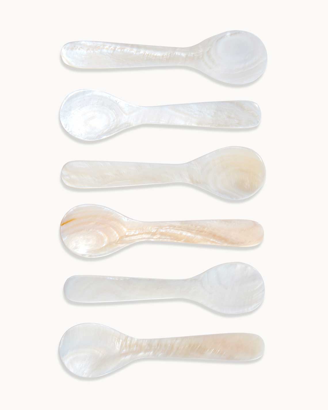 six pearl spoons are carefully arranged next to each other on a white background. each has beautiful individual pearl patterns