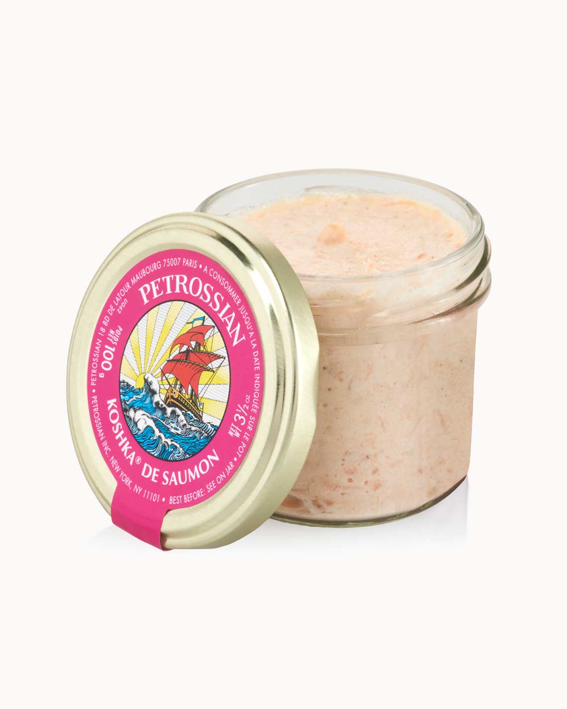 an open glass jar with a copper lid and a pink label is filled with creamy salmon tournade, sitting on a white background.