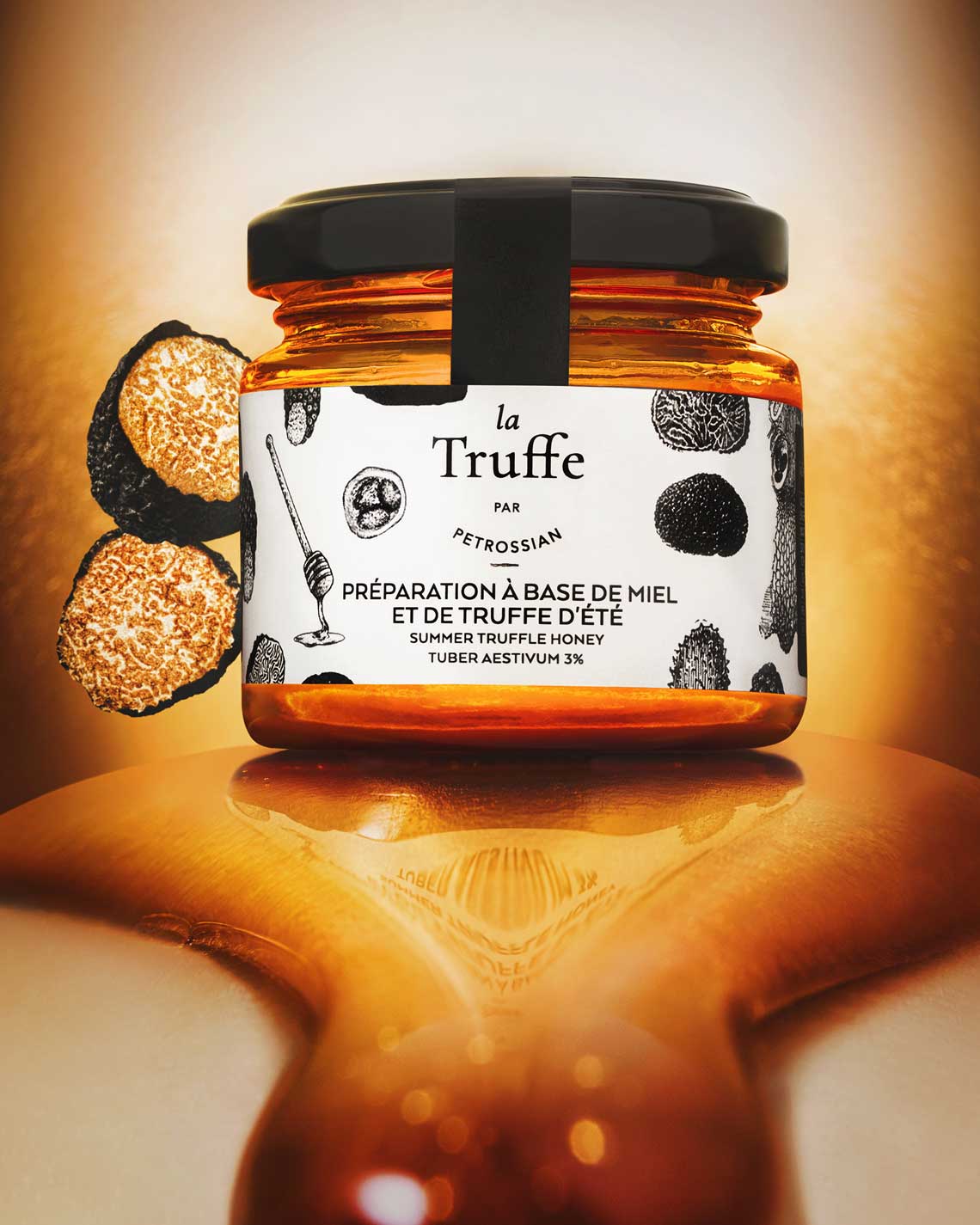 a glass jar of golden truffle honey sits atop a dreamlike oozing puddle of honey, in front of a golden background. Two truffles halves sit next to the jar.