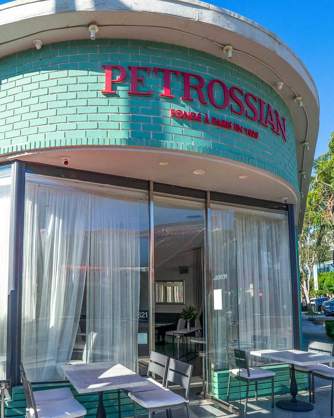 the exterior of the Petrossian restaurant in West Hollywood. The Petrossian name is featured in bright red letters on white brick above a wide glass door.
